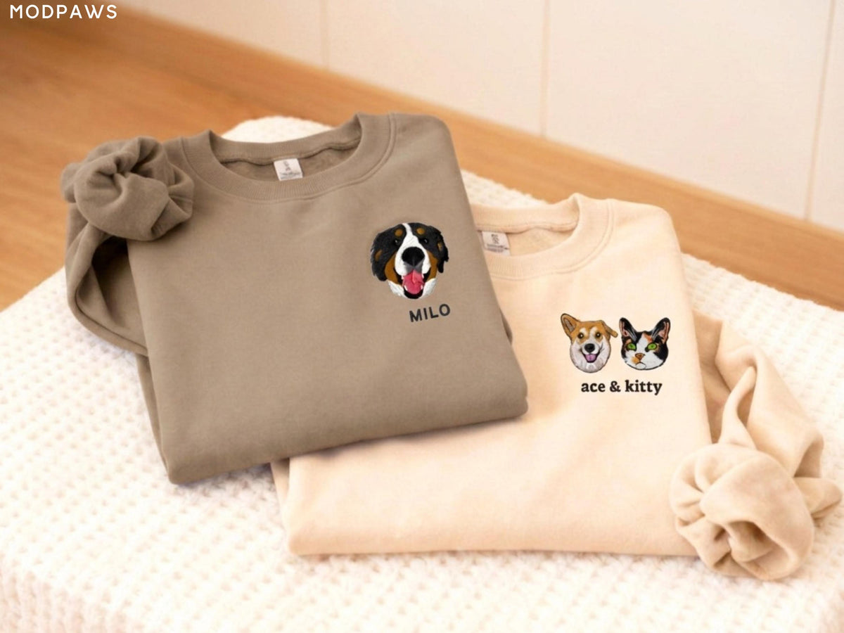 May include: Two crewneck sweatshirts in taupe and cream, each featuring embroidered pet portraits on the left chest. The taupe sweatshirt displays a dog face with the text MILO, while the cream sweatshirt shows a dog and cat with the text ace & kitty.
