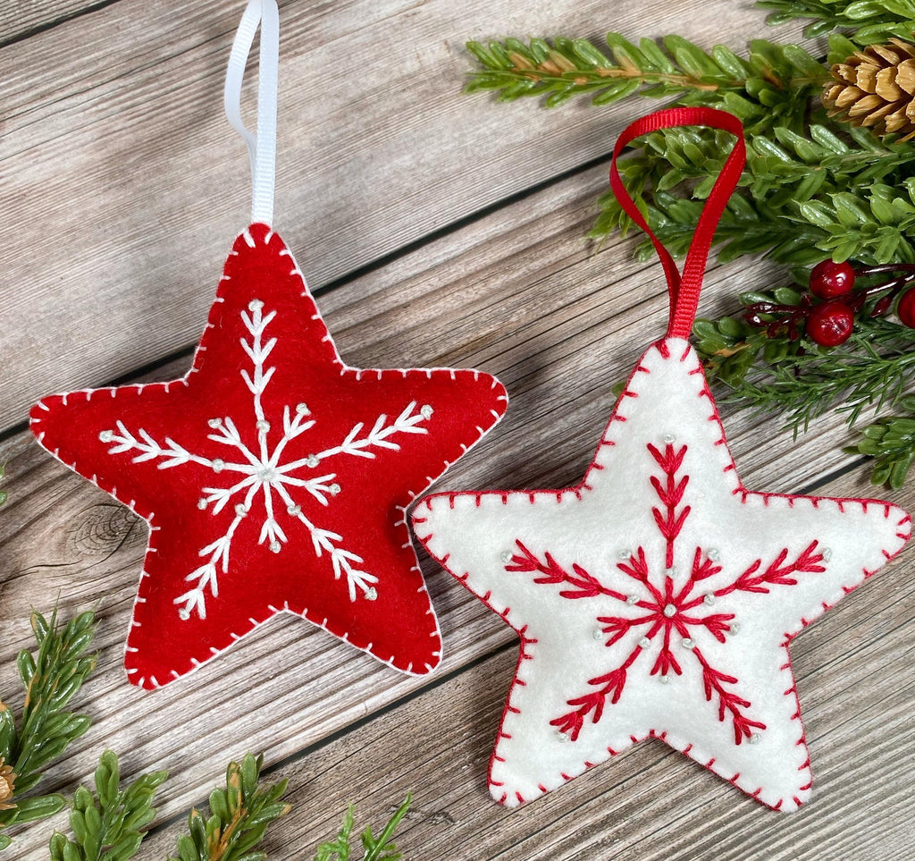 May include: Two felt Christmas ornaments in the shape of stars. One star is red with white snowflake embroidery and the other is white with red snowflake embroidery.