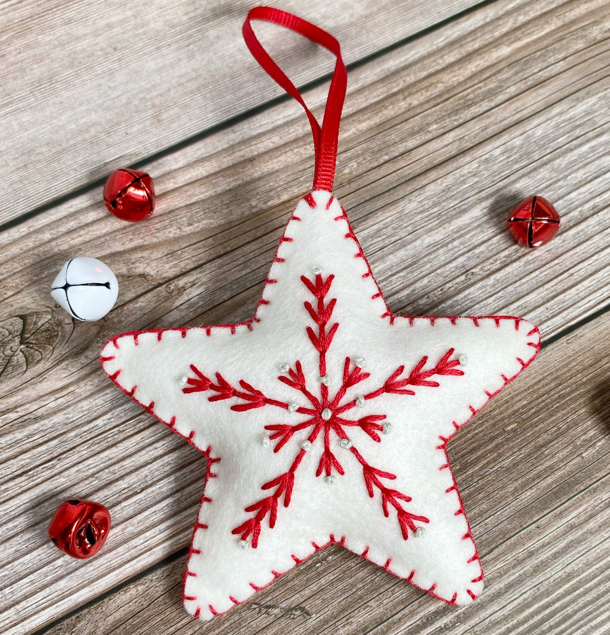 May include: White felt star ornament with a red embroidered snowflake design and a red ribbon for hanging.