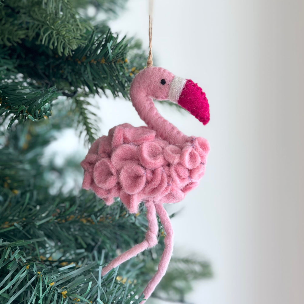 May include: Pink felt flamingo Christmas ornament with a white stripe and a bright pink beak.