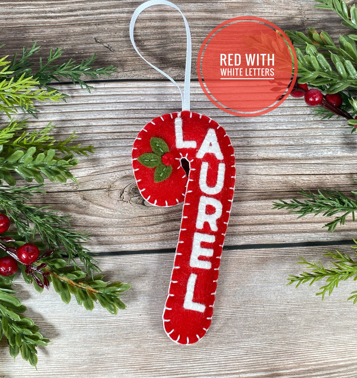 May include: Red felt candy cane Christmas ornament with the name "LAUREL" in white felt letters.